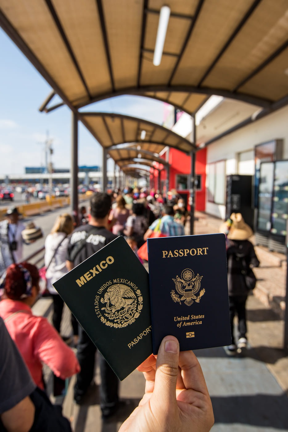 Hand holding U.S. and Mexican passports at a border crossing station