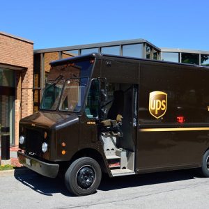 Brown UPS delivery truck parked outside a building for mail delivery