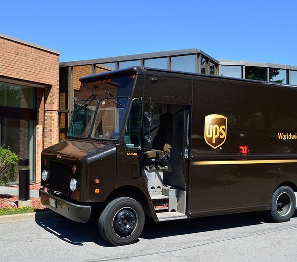 Brown UPS delivery truck parked outside a building for mail delivery