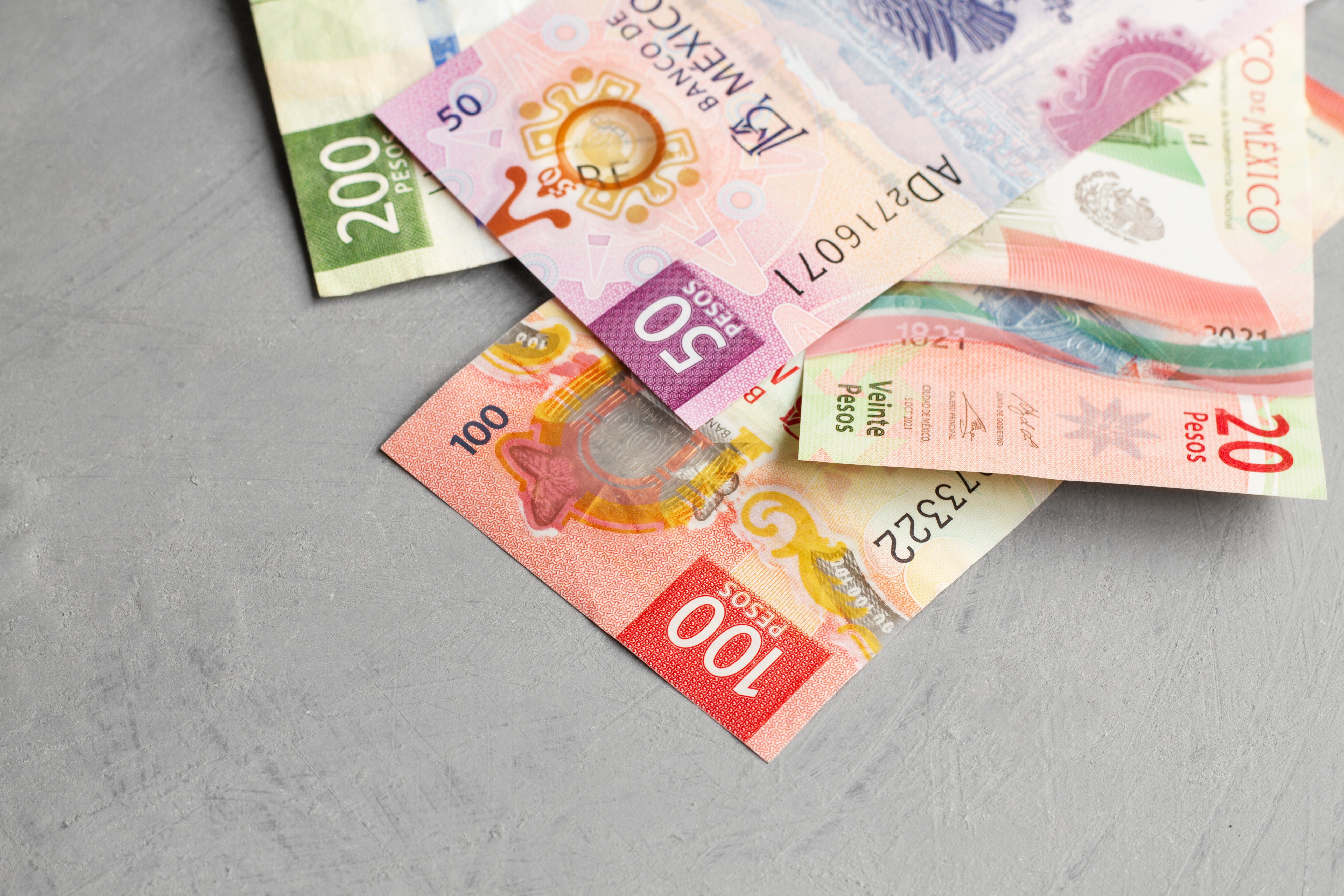 Billetes mexicanos de 20 50 100 y 200 pesos sobre mesa gris - inflacion Mexico 2026