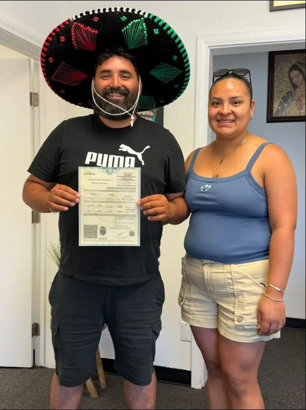Pareja feliz sosteniendo su acta mexicana después de obtener la doble nacionalidad con DNExpress para Fiestas Patrias 2026