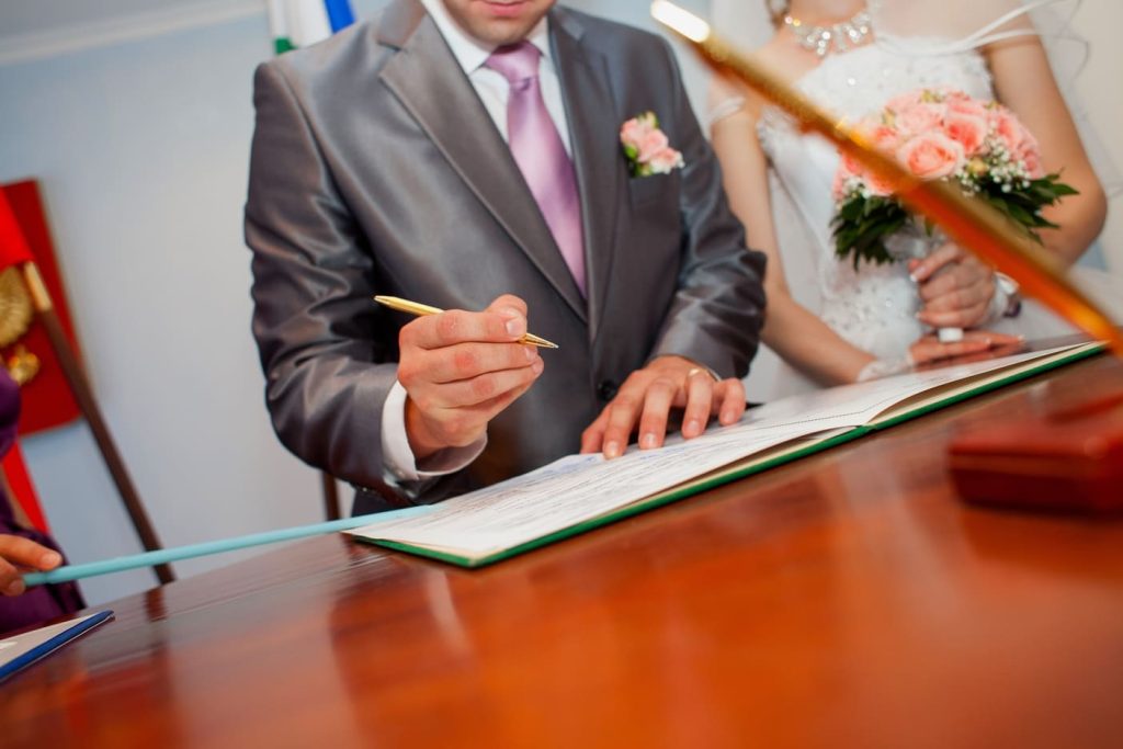 Pareja firmando un certificado de matrimonio en un escritorio de oficina legal